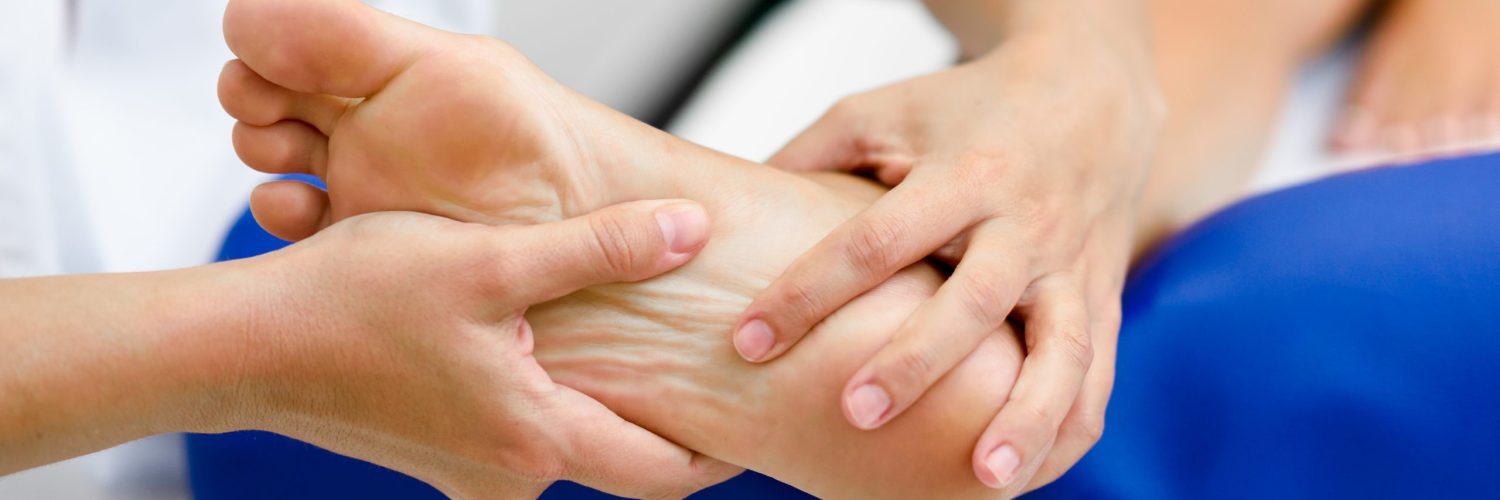 Medical massage at the foot in a physiotherapy center. Female physiotherapist inspecting her patient.